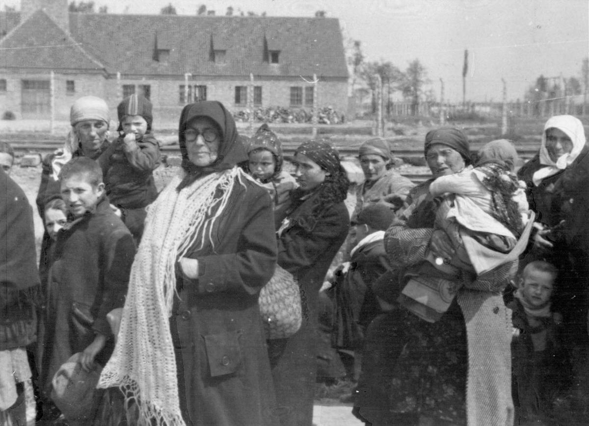 Еврейские женщины и дети стоят перед газовой камерой №3. Их уже приговорили к смерти, но они еще не знают об этом. Биркенау, Польша. Май, 1944 